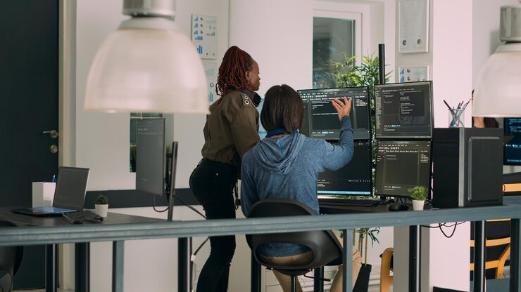 Photo diverse team of database admins analyzing source code and comparing data script in busy agency room. cloud programers working on system interface algorithm in development office.