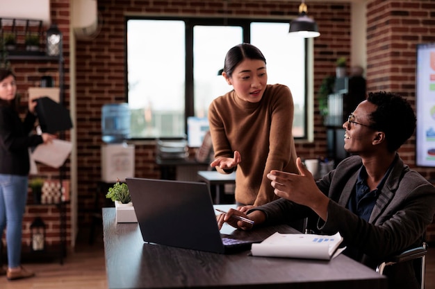 Photo diverse team of people working on laptop in disability friendly office, man with physical health condition at work. company worker with impairment brainstorming ideas with woman.