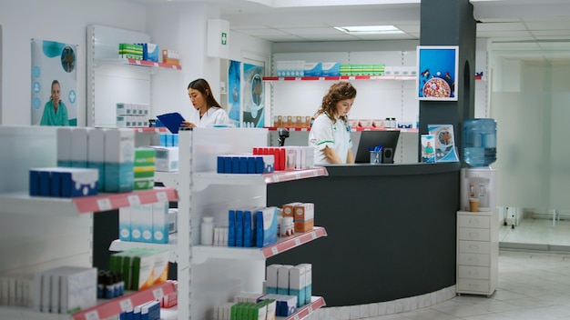 Diverse team of pharmacists working at drugstore counter to sell medicaments and pharmaceutics, looking at pharmaceutical products and boxes of pills. Checking drugs at pharmacy shop.