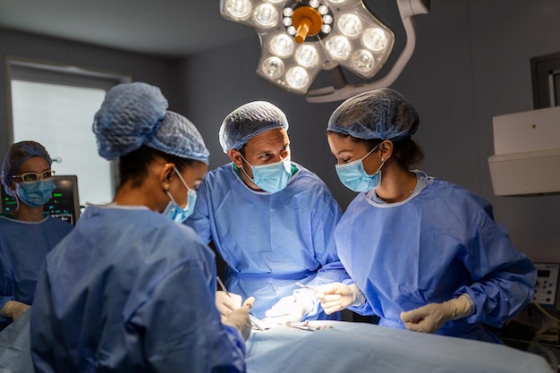 Diverse Team of Professional surgeon Assistants and Nurses Performing Invasive Surgery on a Patient in the Hospital Operating Room Surgeons Talk and Use Instruments Real Modern Hospital