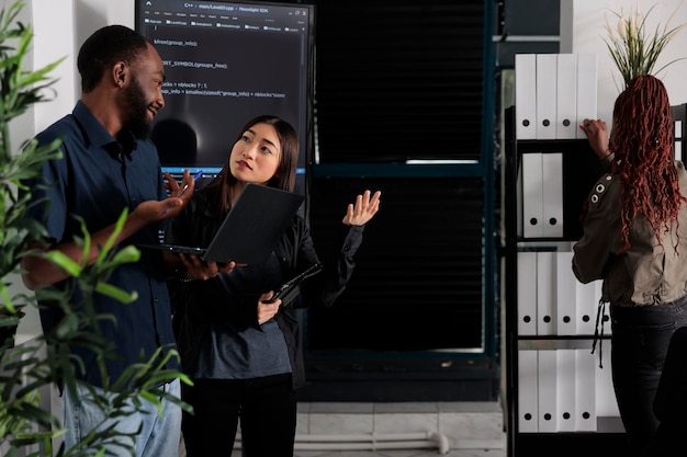 Diverse team of programmer analyzing html code on laptop\
computer, checking artificial intelligence project in it office.\
app developers working on machine learning software, developing new\
interface.