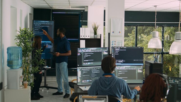 Photo diverse team of software engineers analyzing code on wall screen tv, using digital tablet and working with artficial intelligence. coders parsing cloud computing project with big data.