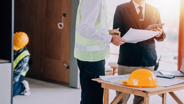 Diverse Team of Specialists Use Tablet Computer on Construction Site Real Estate Building Project with Civil Engineer Architect Business Investor and General Worker Discussing Plan Details