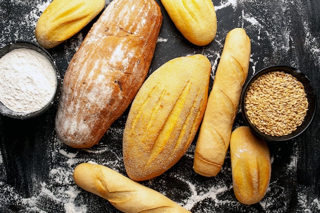 Diverse vers brood en broodjes op een stenen tafel.