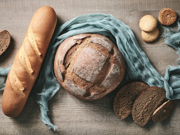 Diverse vers gebakken brood op rustieke houten keukentafel, bovenaanzicht