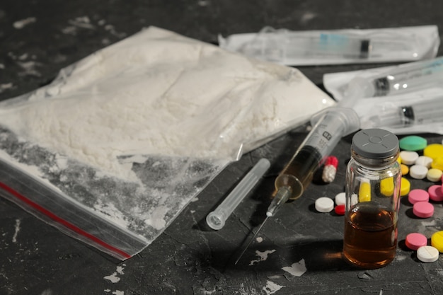Diverse verslavende middelen. cocaïne, heroïne en pillen op een zwarte tafel. Het concept van drugsverslaving.