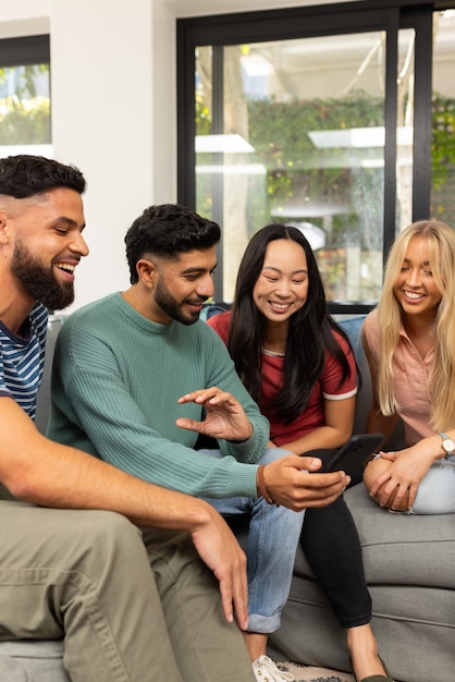 Diverse vrienden zitten op de bank te glimlachen en samen naar een smartphone te kijken.