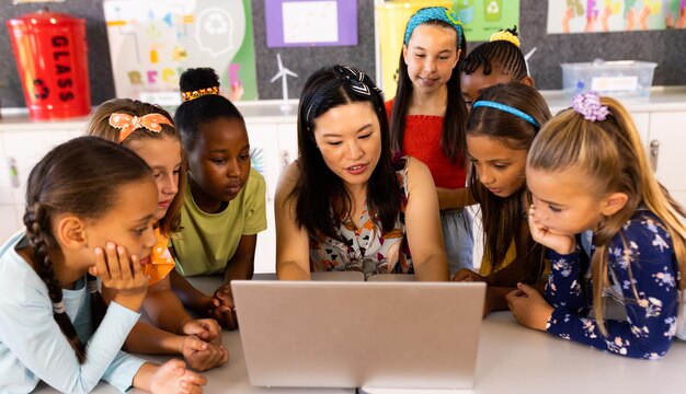 Foto diverse vrouwelijke lerares met laptop en basisscholieren in de klas