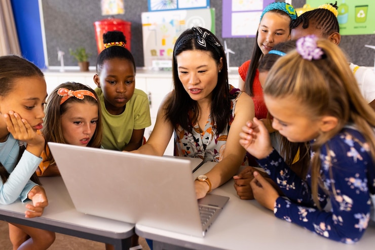 Foto diverse vrouwelijke lerares met laptop en basisschoolmeisjes in de klas