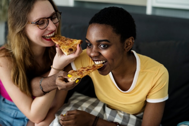 Photo diverse women eating pizza together