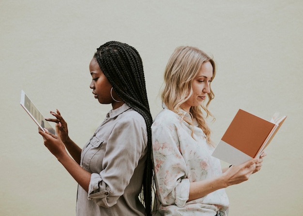 Diverse women reading a book and using a tablet