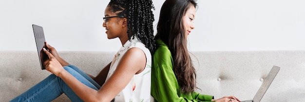 Diverse women sitting together using digital devices