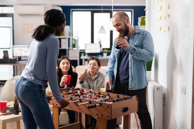 Diverse workers celebrate playing foosball