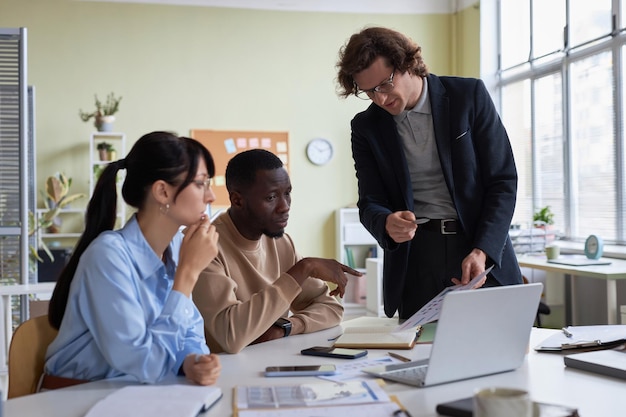 Diverse young business team of three people collaborating on project in office