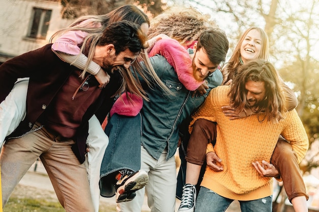 Diverse young of young people playing and joking piggybacking together in the park