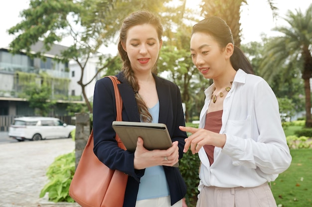 Diverse zakencollega's bespreken document op tabletcomputer wanneer ze buiten staan