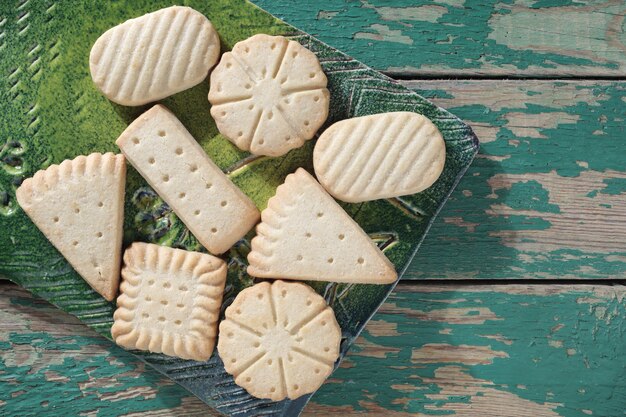 Diverse zandkoekkoekjes op een keramisch bord op oude groene houten hoogste mening als achtergrond