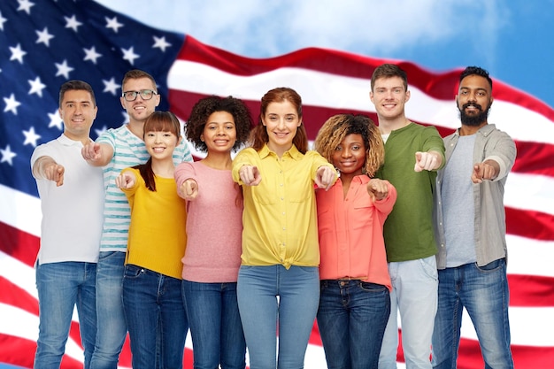 Foto diversiteit, keuze, etniciteit en mensenconcept - internationale groep blij lachende mannen en vrouwen die met de vinger naar je wijzen over de achtergrond van de amerikaanse vlag