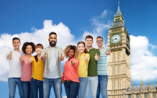 diversiteit, ras, etniciteit en mensenconcept - internationale groep van gelukkig lachende mannen en vrouwen die hun duimen laten zien boven London City en Big Ben Tower-achtergrond