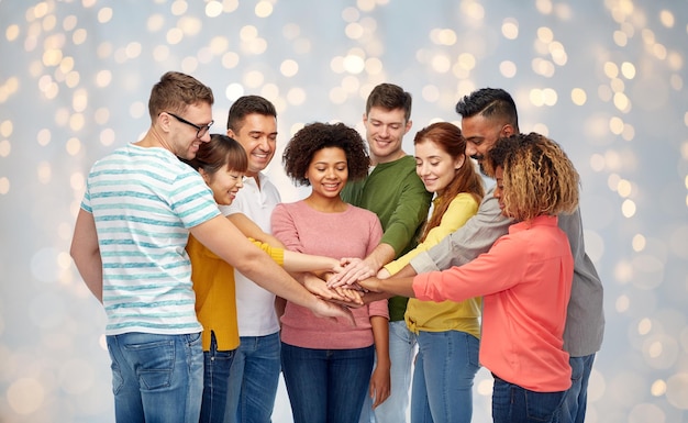 diversiteit, teamwerk, ras, etniciteit en mensenconcept - internationale groep gelukkige glimlachende mannen en vrouwen die elkaar de hand houden tijdens de feestdagen achtergrondverlichting