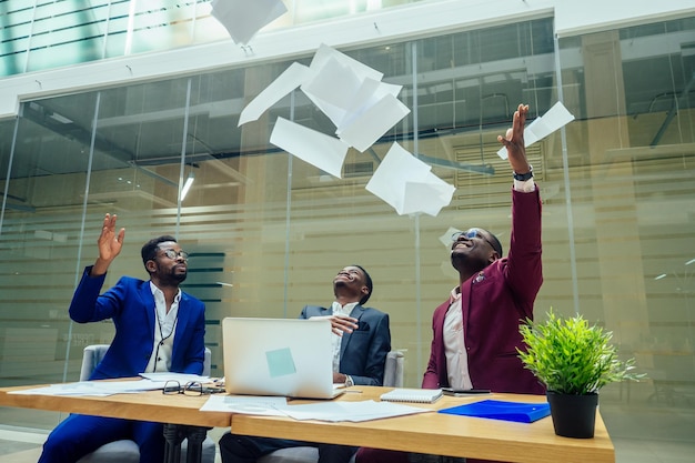 Diversity business people form by different races, Indian, Malay, Indonesian, Chinese documents throwing paper up in modern room.