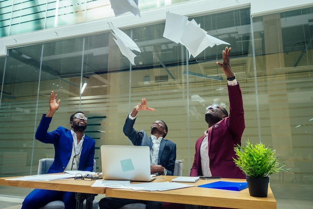 Diversity business people form by different races, Indian, Malay, Indonesian, Chinese documents throwing paper up in modern room.