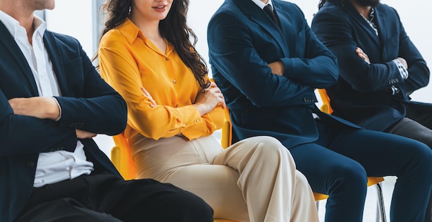 Foto diversità candidati seduti mentre aspettano un colloquio di lavoro con il braccio incrociato in vista laterale sezione bassa immagine ritagliata di uomini d'affari che sorridono con fiducia sala d'attesa moderna intellettuale