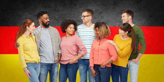 Foto concetto di diversità, immigrazione e persone - gruppo internazionale di uomini e donne sorridenti felici sullo sfondo della bandiera tedesca