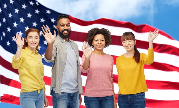 diversity, immigration and people concept - international group of happy smiling men and women waving hands over american flag background