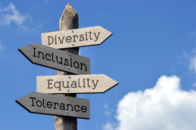 Diversity inclusion equality tolerance wooden signpost with four arrows sky with clouds