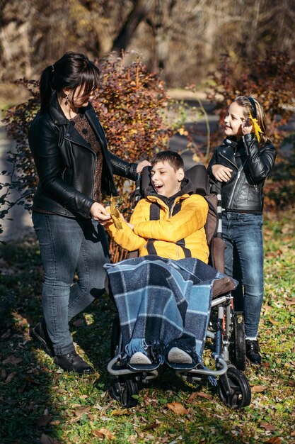 다양성과 포용성 행복한 가족 어머니 딸과 아들이 뇌성마비를 고 있는 십대 소년