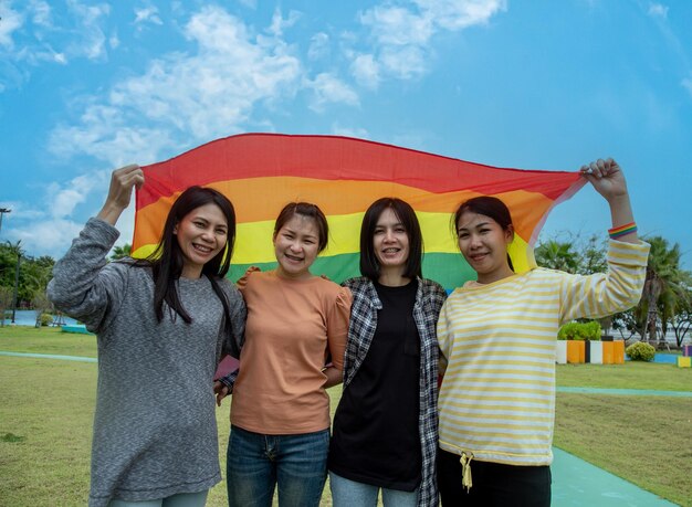 写真 多様性の人々が手を挙げてlgbtコミュニティの象徴であるカラフルなlgbtqレインボーフラッグを掲げる