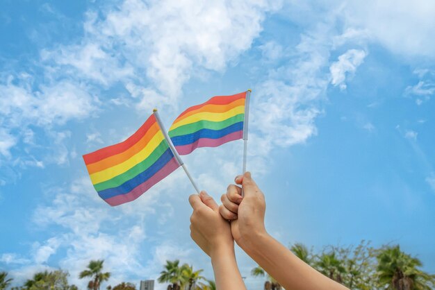 多様性の人々が手を挙げてLGBTコミュニティの象徴であるカラフルなlgbtqレインボーフラッグを掲げる