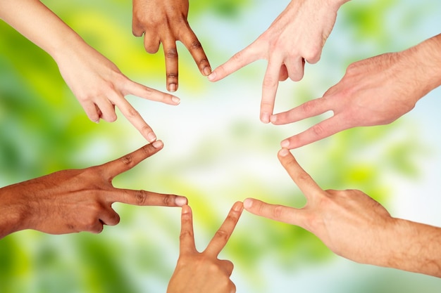 Photo diversity, race, ethnicity, international and people concept - group of hands showing peace hand sign over green natural background