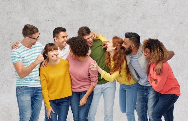 diversity, race, ethnicity and people concept - international group of happy men and women laughing over gray concrete background