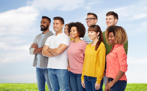 Разнообразие, раса, этническая принадлежность и концепция людей - международная группа счастливых улыбающихся мужчин и женщин на голубом небе и травяном фоне