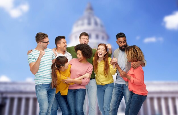 diversity, race, ethnicity, success and people concept - international group of happy smiling men and women celebrating victory over united states capitol background