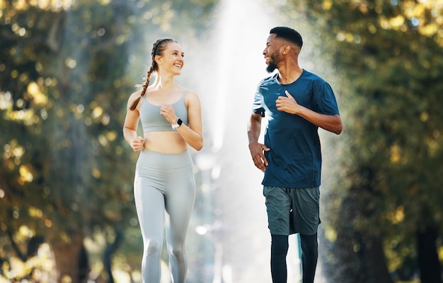 Разнообразный бег и беседа о здоровье пары в парке для тренировок и мотивации спортивного марафона. Межрасовые бегуны, спортсмены, кардиотренировки и здоровый фитнес вместе в лесу.