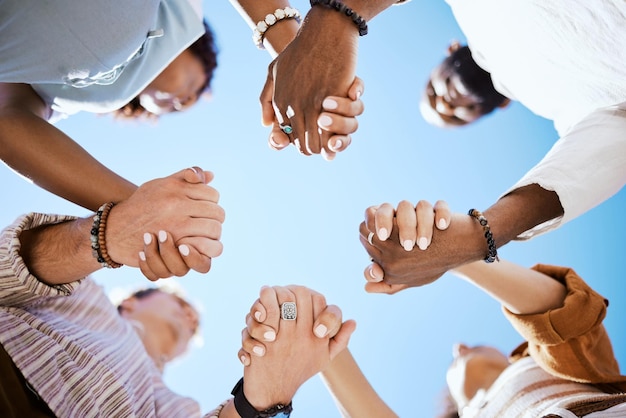 Diversity support and people holding hands in trust and unity for community against sky background Hand of diverse group in solidarity for united team building collaboration and teamwork success