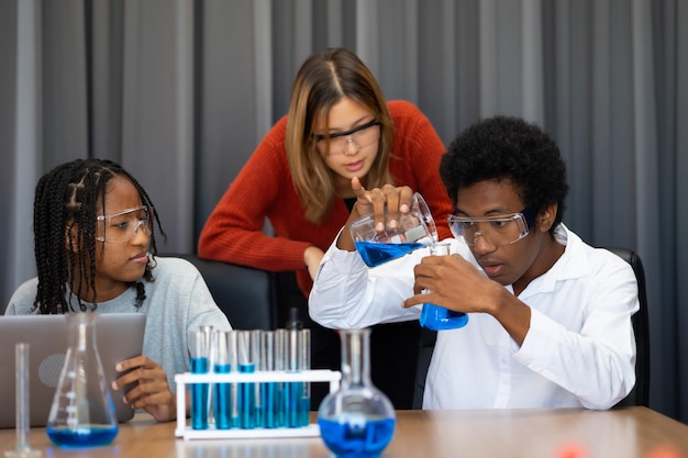 写真 少年と女の子が学校で化学のレッスンで科学実験をしています 化学のクラス 学生の科学ワークショップ