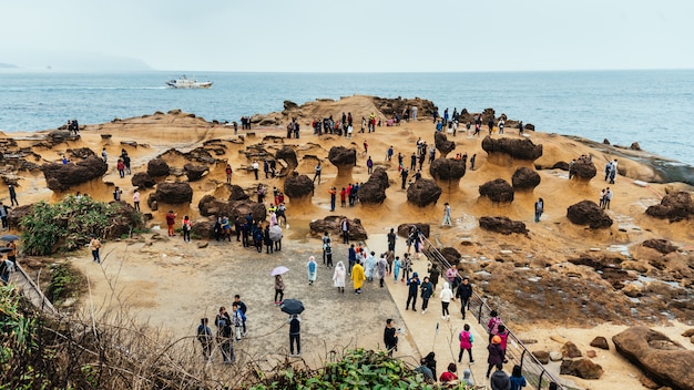 台湾の北海岸の岬である野柳地質公園を歩く観光客の多様性。海に浸食されたハチの巣とキノコの岩の風景。