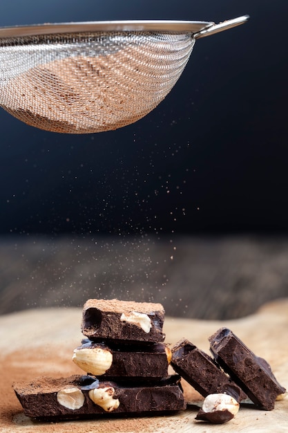 Разделенный на части шоколадный батончик с цельными орехами, сладкий шоколад с дроблеными на кусочки орехами, кусочки шоколада с фундуком с какао и сахаром