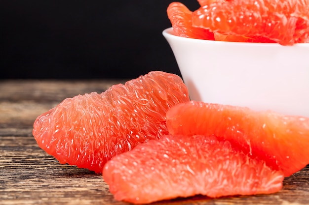 Divided into whole slices delicious sour red grapefruit on the table