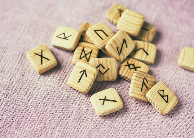Divination on the runes. Wooden runes scattered on the background of the fabric, selective focus.