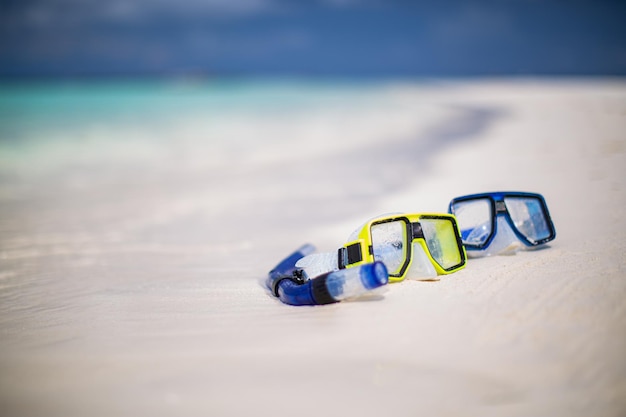 Очки для дайвинга и снаряжение для снорклинга на белом песке возле пляжа. Летний отдых и рекреационные путешествия