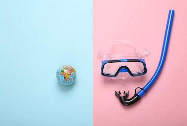diving set with globe on pink blue background travel concept top view