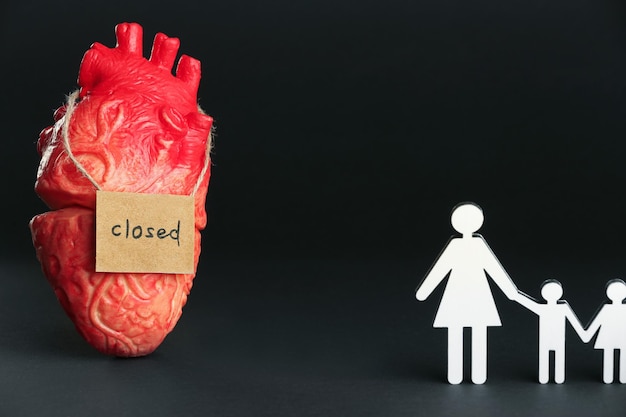 Divorce concept Heart model card with word Closed near paper figures of woman and children on black background