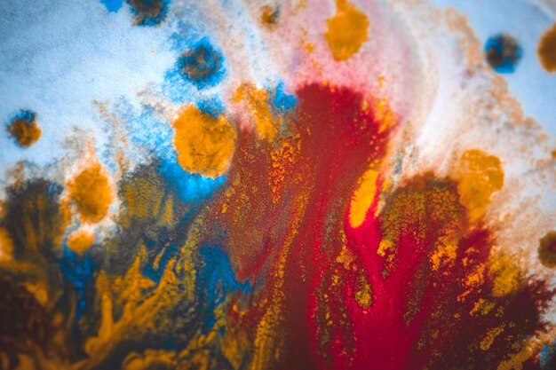 Divorces and paint drips red, orange, yellow, blue blurred abstract background on a white paper background plane surface close-up macro with filter toning effect