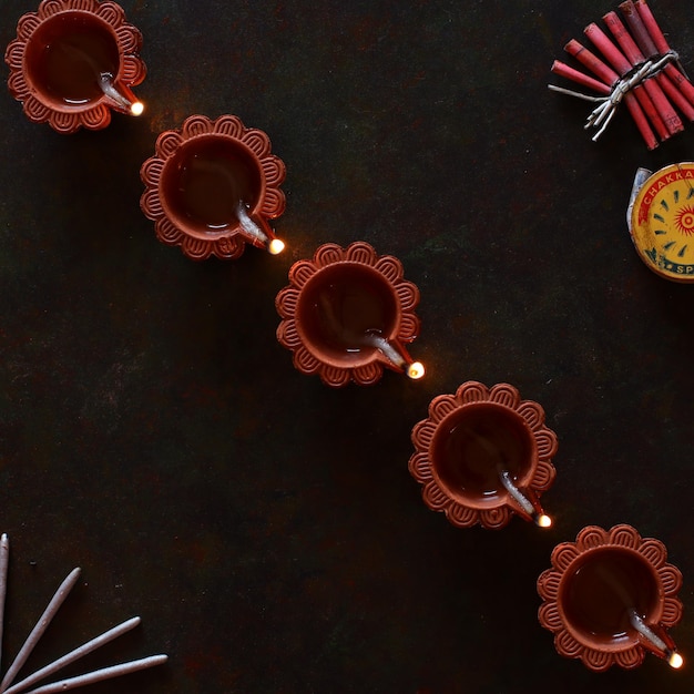 Diwali diya diagonally arranged with firecrackers on black background, happy diwali deepawali