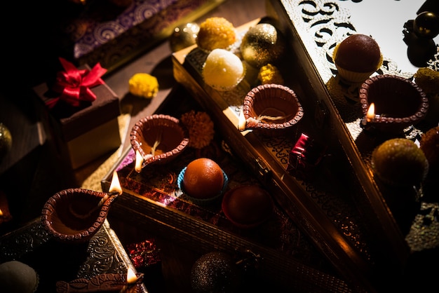 Diwali diya or lighting in the night with gifts, flowers over moody scene